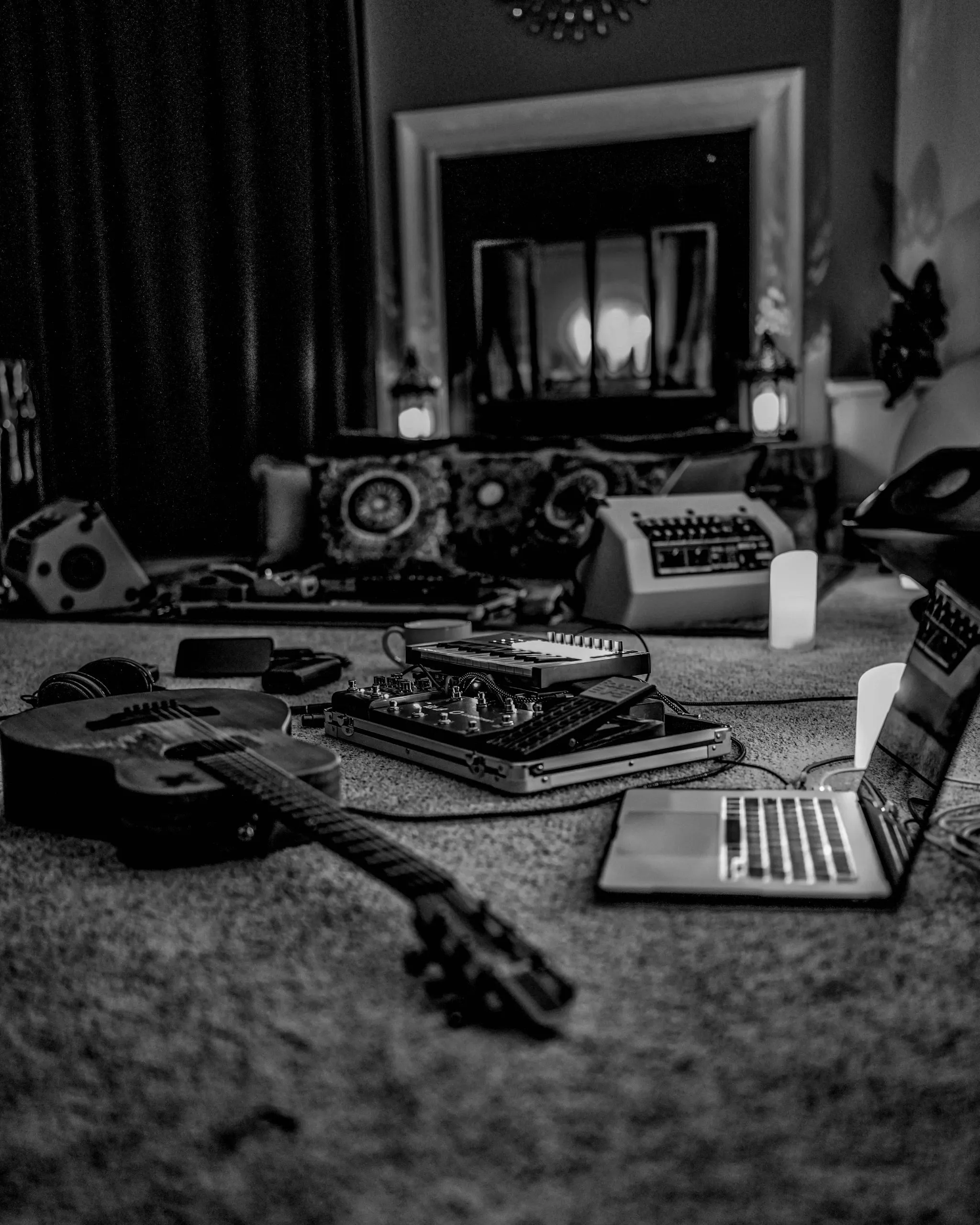 A Musician's Creative Journey Week 22 - a black and white photograph of my acoustic guitar rig in my studio on the floor in front of accandle lit fireplace